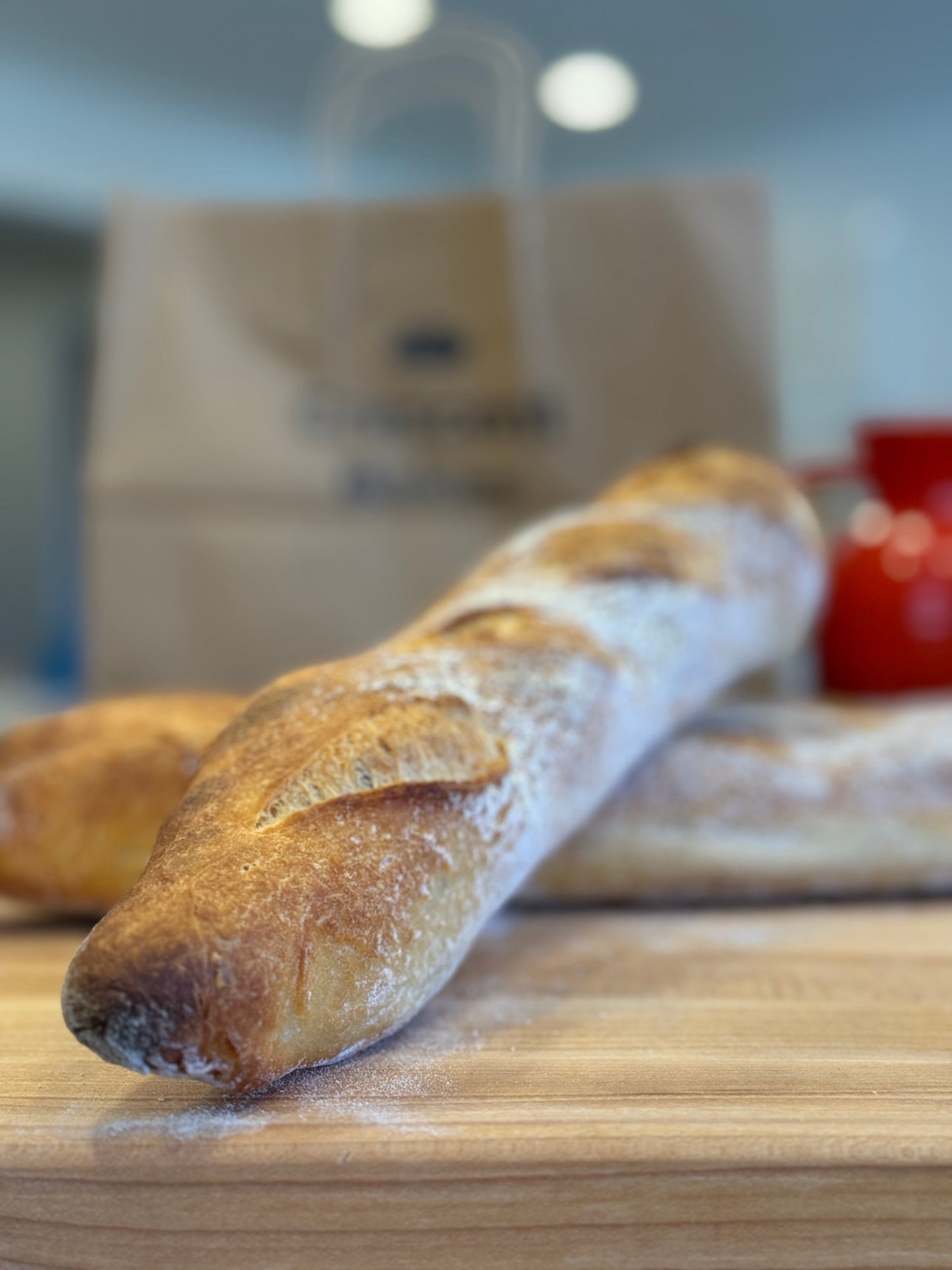 A loaf of Crescent Bakes Sourdough bread on a wooden cutting board with a blurred background.