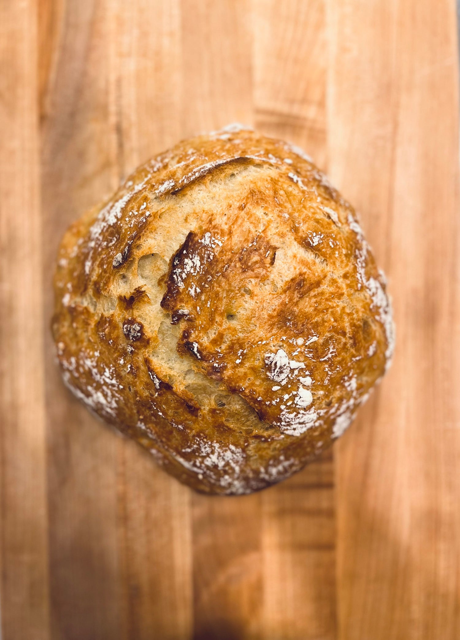 A golden-brown Crescent Bakes loaf of bread with a crispy crust, placed on a wooden surface.