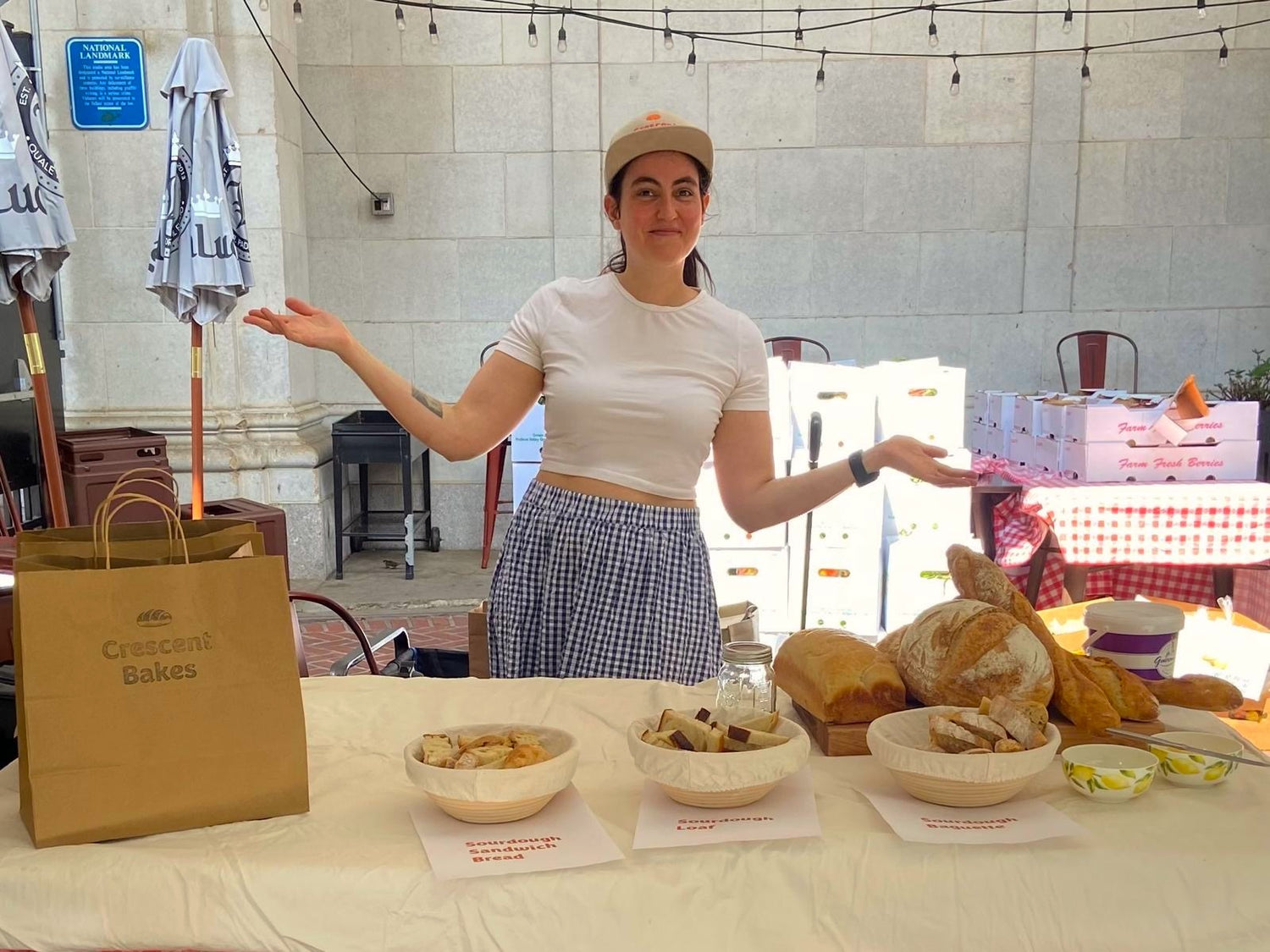 Woman standing behind a table with baked goods and a 'Crescent Bakes' packaging bag.