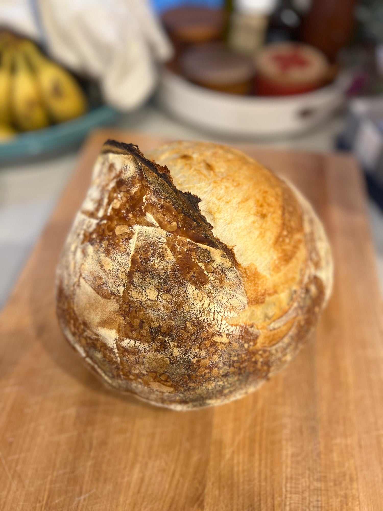 A freshly baked Crescent Bakes sourdough loaf on a wooden cutting board.